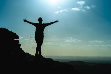 silhouette of woman enjoying view on top of rock with arms wide open in the forest