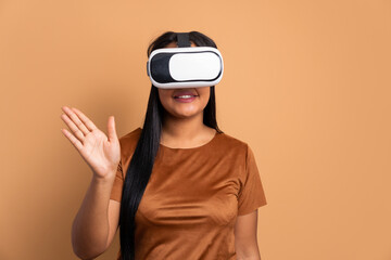 cheerful african american woman Using VR headset and gesturing in beige studio background. virtual reality, technology simulation concept.