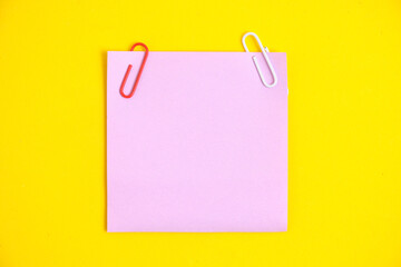 Lilac sticker for notes and paper clips yellow background.