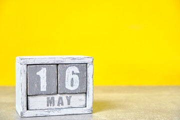 May 16 calendar made wooden cubes yellow background.With an empty space for your text.
