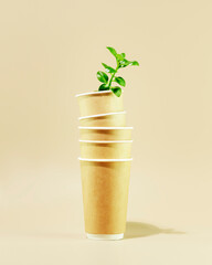 Fototapeta na wymiar Concept of ecology, conservation, plastic free and recycling. Sustainable minimalistic still life with green shoot in disposable eco friendly cardboard cups on beige background. Vertical format
