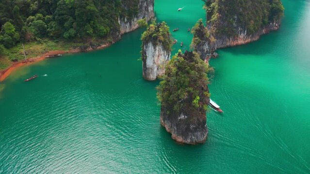 Three limestone rocks Three Brothers at Cheow Lan Lake, Khao Sok National Park, Surat Thani Province, South of Thailand. Aerial view 4K.