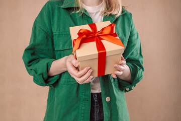 Close up shot of successful woman with gift box wrapped with red ribbon, studio photo over...