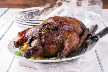 Traditional roasted stuffed Christmas duck with apples and potatoes served as close-up on a classic design plate on a rustic wooden board