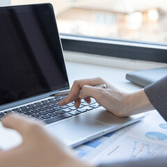 Finance workers are reviewing the company's financial data on a laptop and using smartphones to communicate or chat with the team at social distances, Working during the virus outbreak.