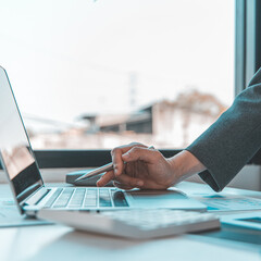 Finance workers are reviewing the company's financial data on a laptop and using smartphones to communicate or chat with the team at social distances, Working during the virus outbreak.