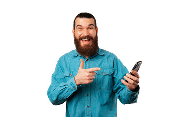 Handsome smiling bearded man is pointing at the smart phone he is holding.