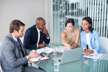 Reviewing the financial data. a group of businesspeople discussing work on a laptop during a meeting.
