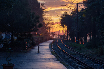 small railway station, rails in the rays of the sun against the background of the sunset and the city of Batumi, the area of the botanical garden