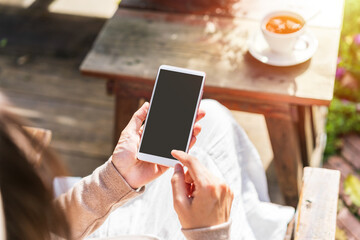 Young female with cup of coffee using mobile phone and relaxing in cafe, Modern lifestyle