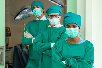 Obraz na płótnie Canvas Multidisciplinary teamwork Three doctor portrait in green coat surgical gown with stethoscope standing arms crossed smiling in operating room. Group surgeon doctor portrait in hospital