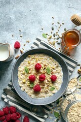 Healthy breakfast. Oatmeal porridge with raspberries, sunflower seeds, pistachio and honey. Top view.