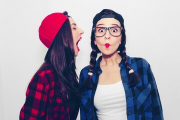 Colorful comic emotional hipster twin girls in baseball cap, topless, smile, cover mouth with hands, surprised and show tongue. Isolated on a light background.