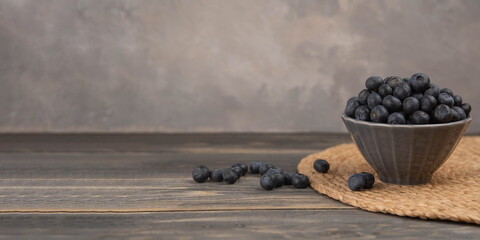Bowl of fresh blueberries on rustic wooden table. Healthy organic seasonal fruit background.