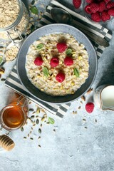Healthy breakfast. Oatmeal porridge with raspberries, sunflower seeds, pistachio and honey. Top view.