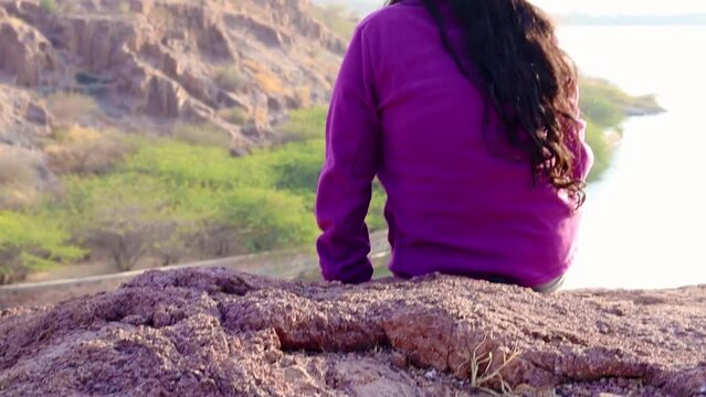 isolated young girl at mountain top with lake view backbit shot from flat angle