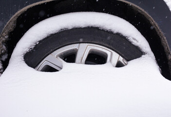 Wheel covered with snow. Heavy city snowfall concept. Winter season.