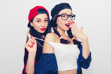 Colorful comic emotional hipster twin girls in baseball cap, topless, smile, cover mouth with hands, surprised and show tongue. Isolated on a light background.