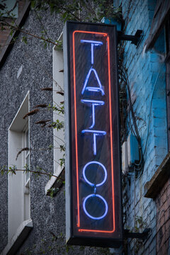 Neon Tattoo Shop Sign On Side Of Building