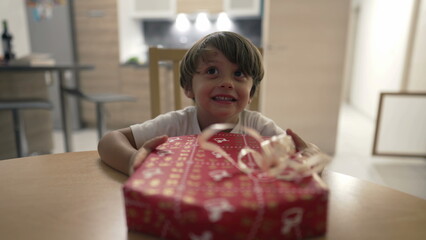 Child opening present. One small boy unwrapping gift