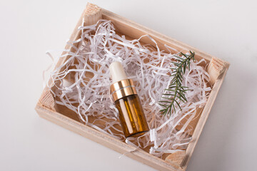 a glass bottle with a pipette for oil and perfume and a fir twig. Aromatherapy, spa salon concept