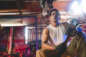 Portrait of a confident Asian male mechanic holding wrench at garage, Auto mechanic standing against a car in a repair garage for using in business of car, expertise mechanic working in automobile
