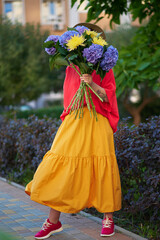woman in red shirt holding a bouquet of blue hydrangea on the background of green garden , spring summer concept. High quality photo