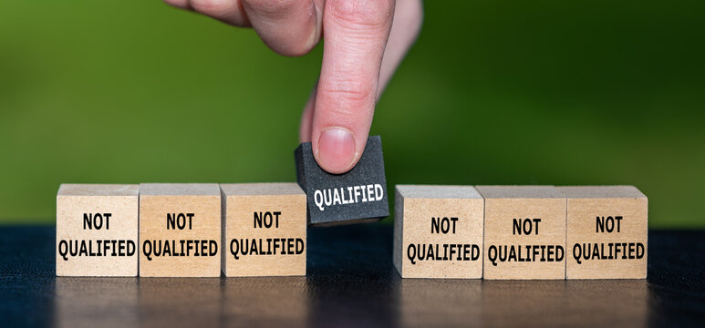 Symbol for finding a qualified candidate. Hand picks wooden cube with the text 'qualified' instead of cubes with the text 'not qualified'.