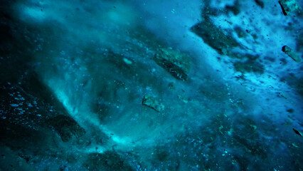 Obraz na płótnie Canvas Turquoise pure color of ice inside the ice cave. Stones and icicles are visible in places. Light grains of snow on the ice walls. Frozen air bubbles in an ice wall. An ancient glacier. Color gradient