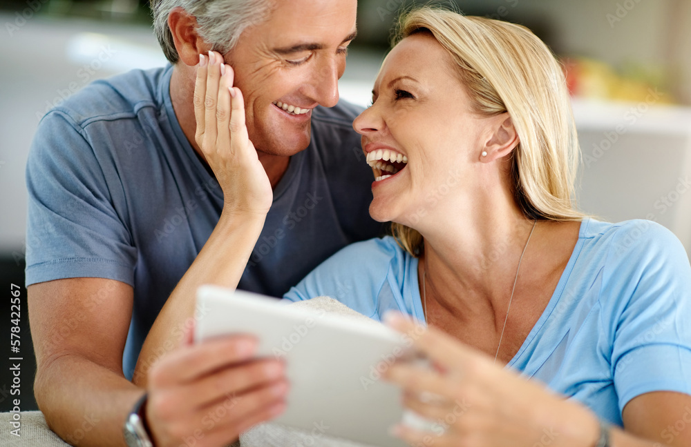 Poster Who doesnt like a good meme. an affectionate mature couple laughing while using a digital tablet on the sofa at home.