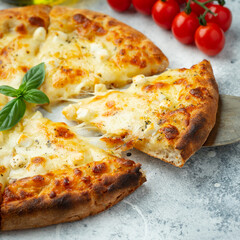Italian pizza four cheeses with stretching cheese and basil on a light concrete background