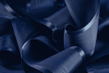 Dark blue abstract background. Swirling roll of  satin fabric.Selective focus.