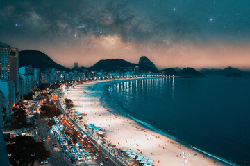 panoramic aerial view at night to Copacabana beach and buildings in Rio de Janeiro under the stars and Milky Way in the background