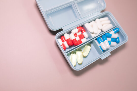 Pill box daily take a medicine, with colorful of pills, tablets, and capsules on beige bacground. Medicine, health concept.
