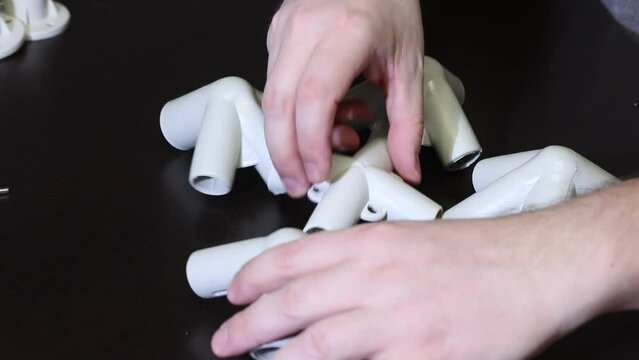 A man demonstrates a set of parts for a garden awning. Looking at adapters. Close-up.