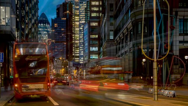 Evening time lapse of Liverpool Street in the City of London with cars and buses zooming past the illuminated skyscrapers in the background