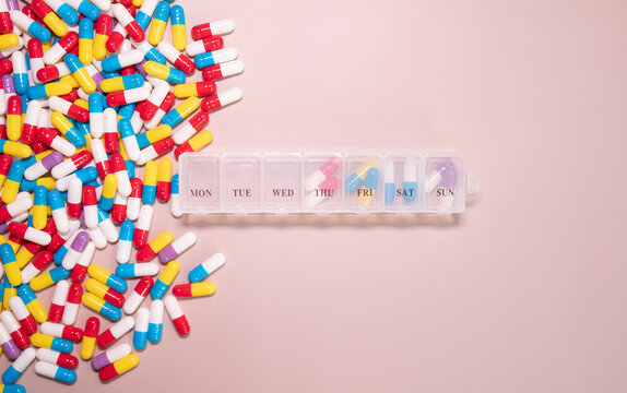 Pill box daily take a medicine, with colorful of pills, tablets, and capsules on beige bacground. Medicine, health concept.