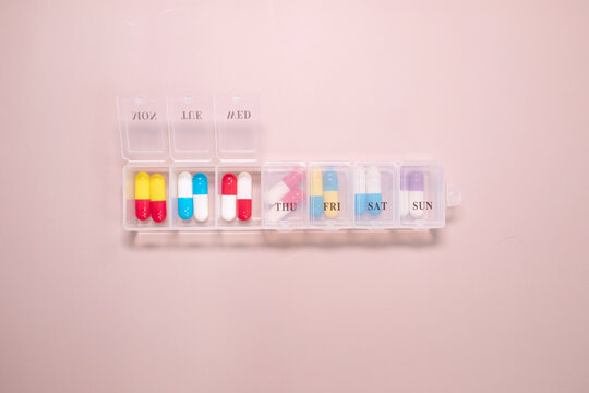 Pill box daily take a medicine, with colorful of pills, tablets, and capsules on beige bacground. Medicine, health concept.