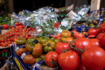 Market stall with a wide range of fresh produce for sale, at Borough Market, urban covered market in Southwark, east London UK. Fresh tomatoes in the foreground.