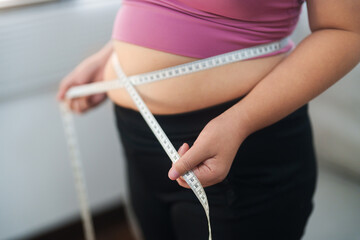 Close up overweight woman measuring her hip with tape measure.. - obrazy, fototapety, plakaty