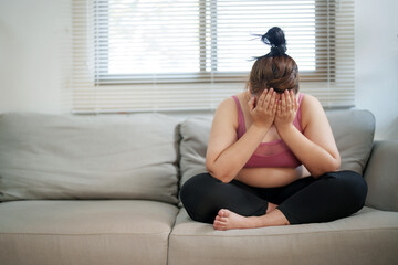 overweight woman sitting on the sofa stress about loss weight..