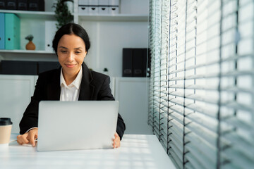 This photo depicts a young African American and competent woman at her workplace. A female employee...