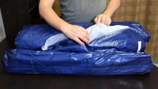 A man examines a tent for a garden. Demonstrates a mosquito net. Medium plan.