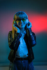 woman with headphones listening to music and dancing in neon light at studio.