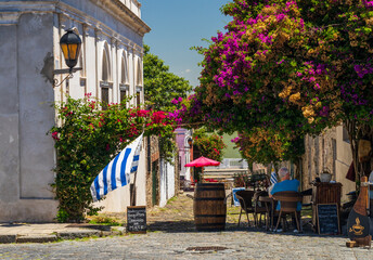 Small cobblestone street leading to river with restaurant in Colonia del Sacramento Uruguay - obrazy, fototapety, plakaty