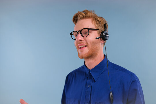 Call Center Employee Talking With A Headset On His Head With Microphone Isolated On Blue Background