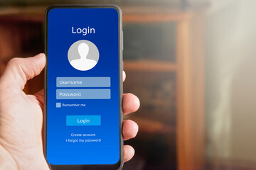Man Man holding mobile phone showing login interface on mobile phone screen, with username and password boxes and login button to access personal account in mobile application.