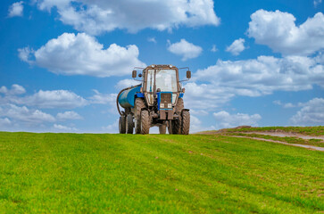 An agricultural tractor drives along a field road. Spring Field