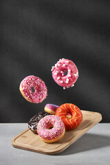 Creative composition of various donuts. A set of donuts with different color glaze on a wooden board. Donuts with chocolate, erysipelas icing, marshmallows and various flavorings. 