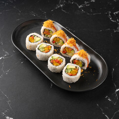 Vegan sushi with vegetables and avocado slice on a black plate. Vegan food concept. healthy colored food